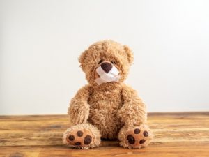 Bild: teddy sitzt mit Pflaster über dem Mund