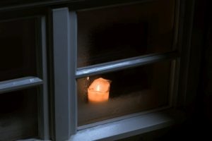 Bild: Kerze steht im Fenster und leuchtet