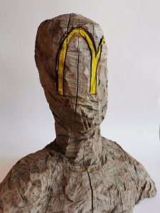 Bild: Skulptur Holzkopf mit McDonalds Emblem