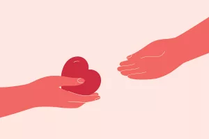 Eine Hand übergibt einer anderen Hand ein Herz.